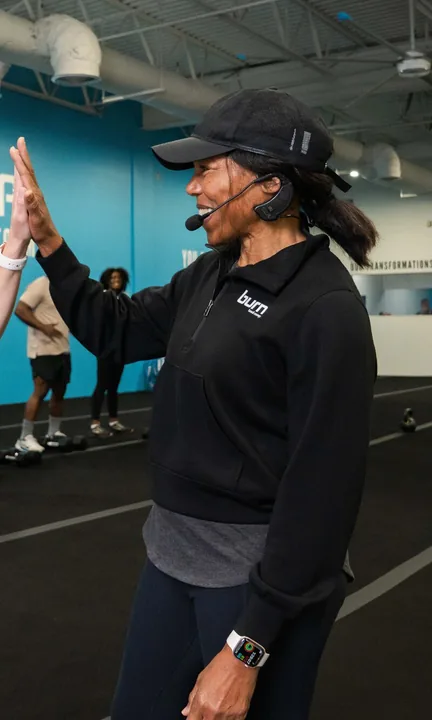Burn Boot Camp short-form post: a trainer in a black pullover high-fiving a member in a gym with blue walls.