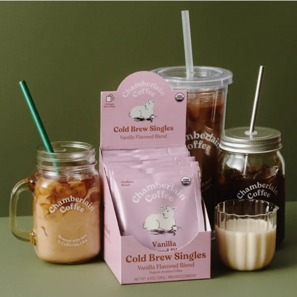 Chamberlain Coffee short-form post: a pink box of vanilla cold brew singles beside iced coffee in a mason jar and a cup on an olive green background.
