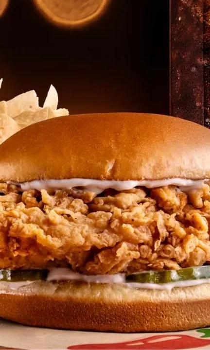 Chili's short-form post: a crispy chicken sandwich with fries on a wooden board in warm restaurant light.
