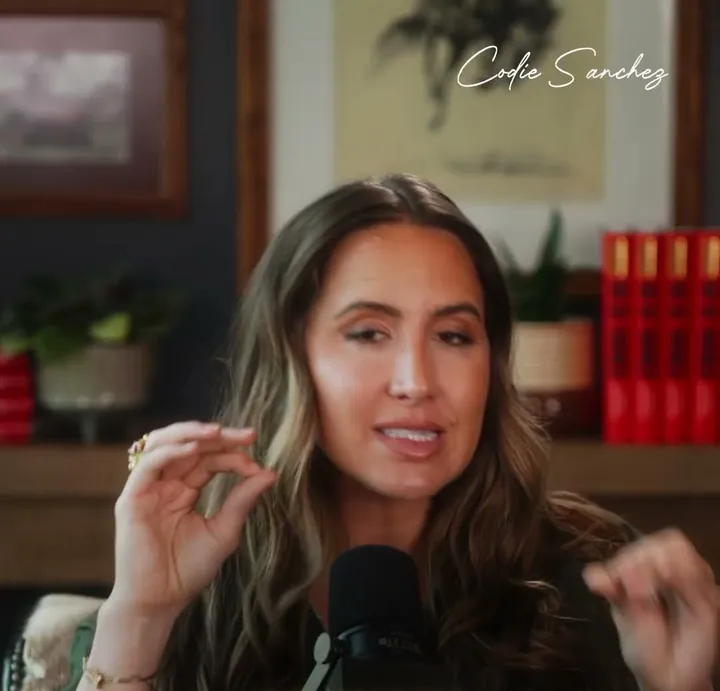 Codie Sanchez short-form post: a woman in front of a bookshelf gesturing as she speaks to a podcast microphone.
