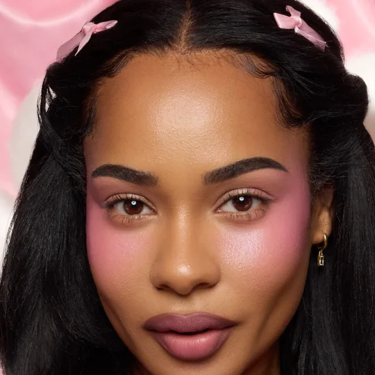 ColourPop short-form post: a woman with pink bows in her hair and a bright pink liquid blush swept across her cheeks.