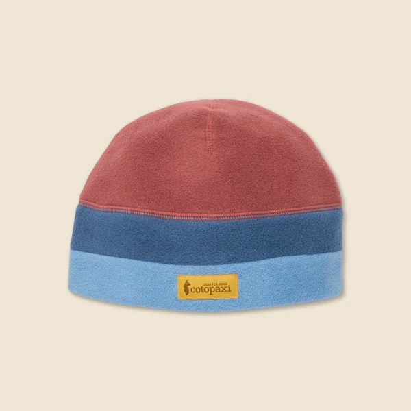 Cotopaxi short-form post: a Teca Fleece Beanie in dusty red, slate blue and sky blue bands with a yellow Cotopaxi patch, on a cream background.