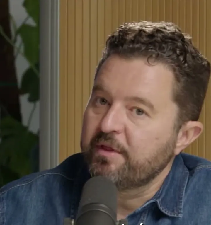 Daniel Priestley short-form post: a bearded man in a denim shirt talking at a podcast microphone.