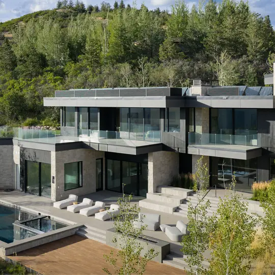 Douglas Elliman short-form post: a modern glass and concrete house with a terrace and pool on a wooded hillside.