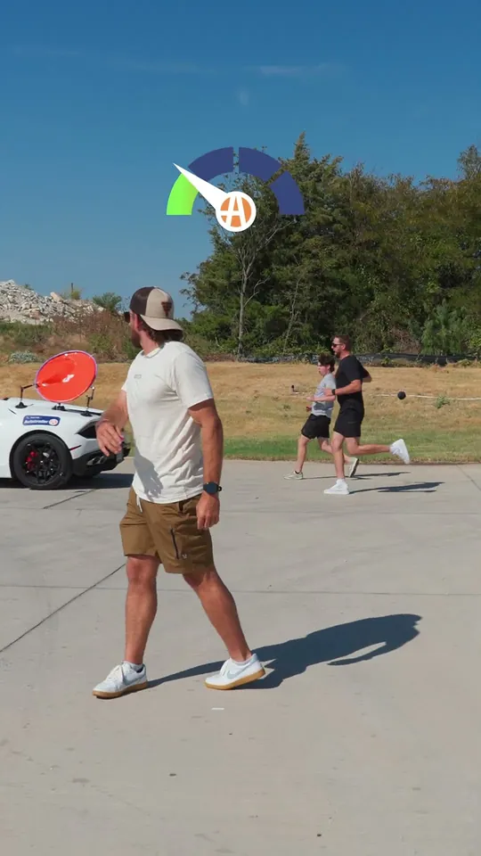Dude Perfect short-form post: a man in a cap and shorts on a sunny street, with a spinning target in the air behind him and a white sports car.