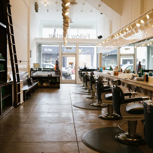 Fellow Barber short-form post: a long, bright barbershop with a row of chairs, shelves of products and a ladder along the wall.