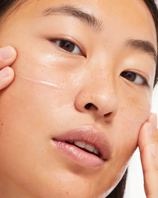 Glossier short-form post: a close-up of a face with Milky Jelly Cleanser being worked into the cheek.