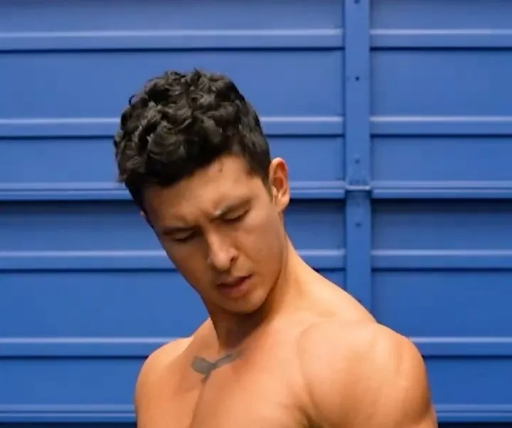 Jeremy Ethier short-form post: a shirtless man looking down at his arm in front of a blue wall.