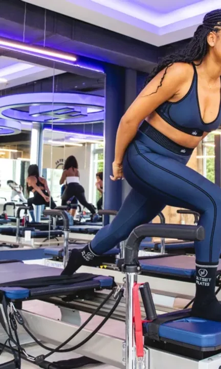 JETSET Pilates short-form post: two women in navy leggings working on reformer machines under blue studio lighting.