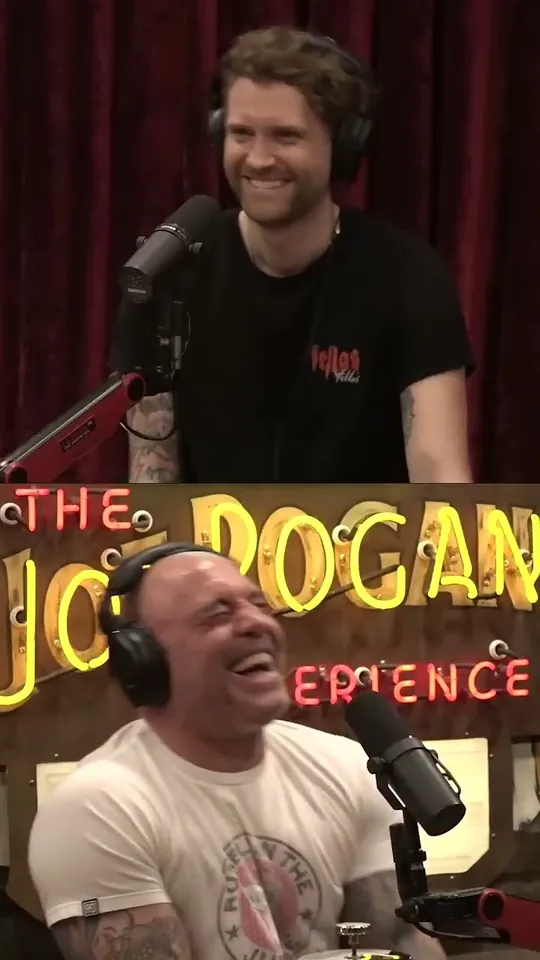 The Joe Rogan Experience short-form post: Joe Rogan in a headset at the microphone under the show's neon sign, with a guest standing above him.