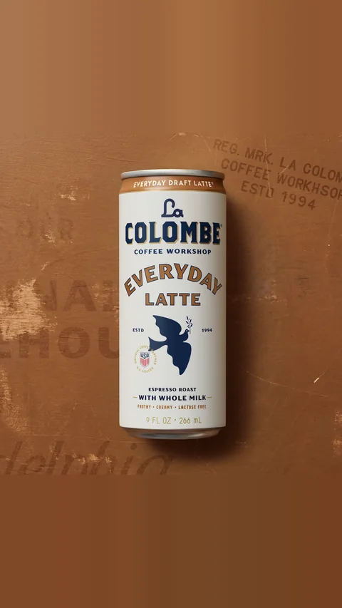 La Colombe short-form post: an Everyday Draft Latte can lying on a brown printed paper surface.