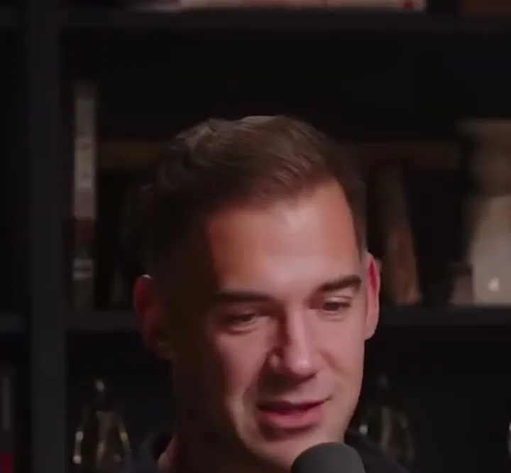 Lewis Howes short-form post: a man in a black shirt talking on a podcast set with bookshelves behind him.