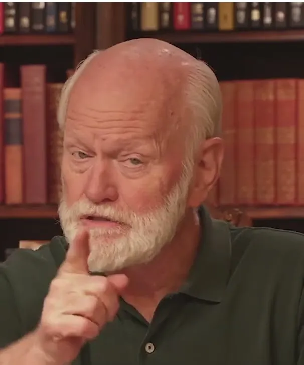 Marshall Goldsmith short-form post: an older man with a white beard in front of a bookshelf, resting his hand on his chin.