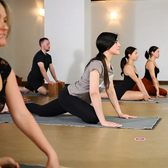 Modo Yoga short-form post: students stretching on mats in a warm-lit yoga studio.