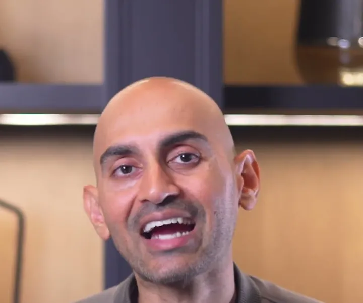 Neil Patel short-form post: a bald man in a grey jacket smiling and talking to camera in front of wooden shelves.