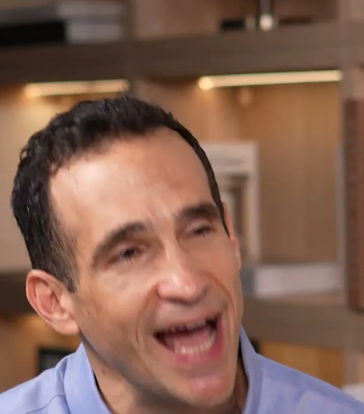 Nir Eyal short-form post: a smiling man in a light blue shirt talking to camera in front of wooden shelves.