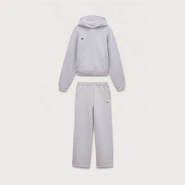 Pangaia short-form post: a pale grey marl hoodie laid above matching straight-leg track pants on a light warm background.