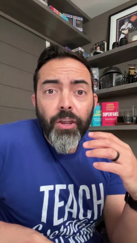 Pat Flynn short-form post: a bearded man in a blue 'Teach' t-shirt pointing at the camera in front of a shelf.