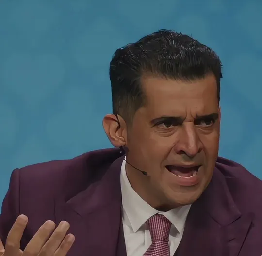 PBD Podcast short-form post: a man in a purple suit speaking on stage in front of a blue backdrop.