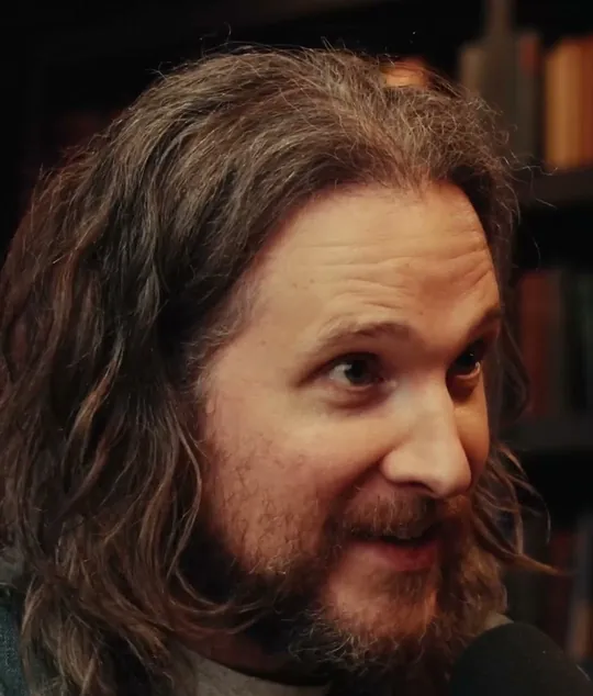 Peter McKinnon short-form post: a man with long hair and a beard speaking to camera in front of a bookshelf.