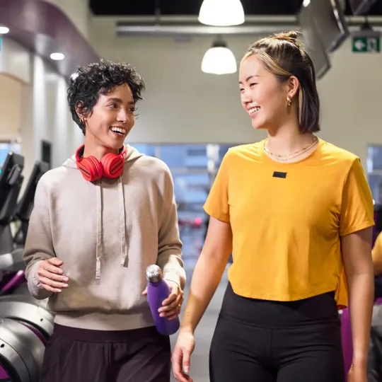 Planet Fitness short-form post: two people chatting and smiling as they walk through a gym.