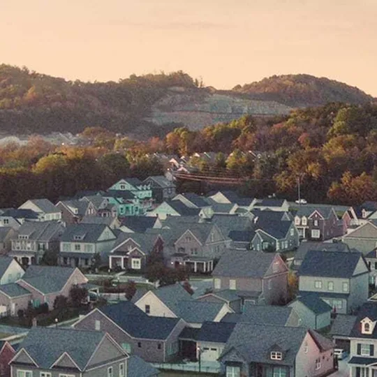 Redfin short-form post: an aerial view of rooftops and hills in a neighborhood at golden hour.