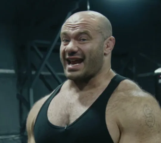 Renaissance Periodization short-form post: a muscular man in a black tank top at a cable machine in a dark gym.