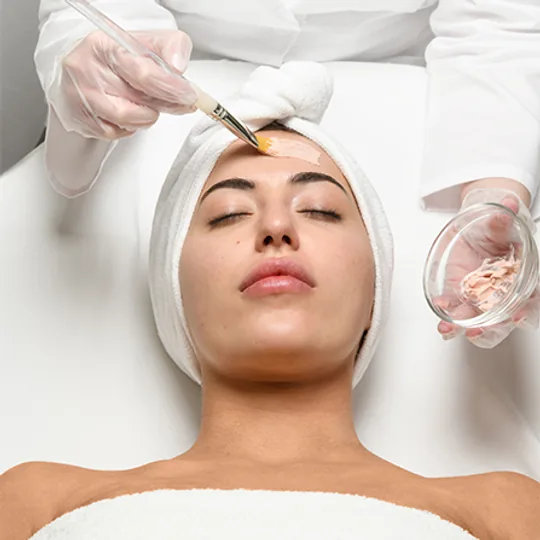 Restore Hyper Wellness short-form post: a woman in a white headband lying back as gloved hands apply a golden mask to her face.