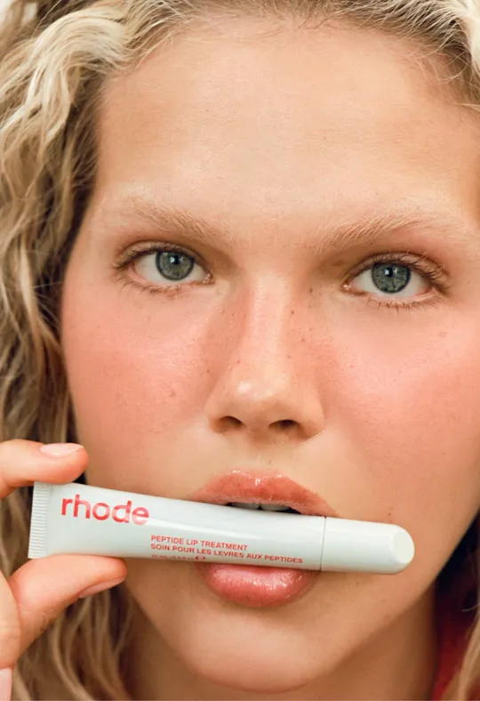 Rhode short-form post: a model holding a Peptide Lip Treatment tube up to her lips.
