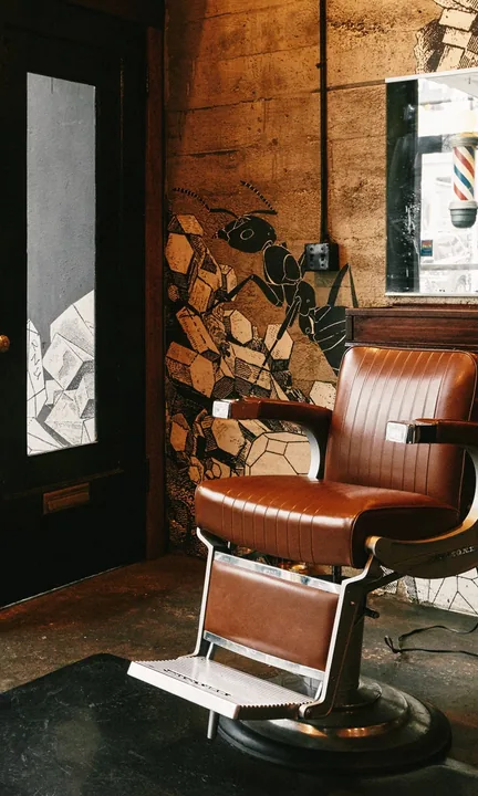 Rudy's Barbershop short-form post: a leather barber chair beside a brick and wood wall in a shop with a glass door.