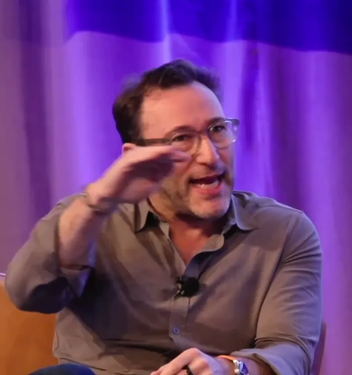 Simon Sinek short-form post: a man in a grey shirt and glasses gesturing as he speaks, in front of a purple curtain.
