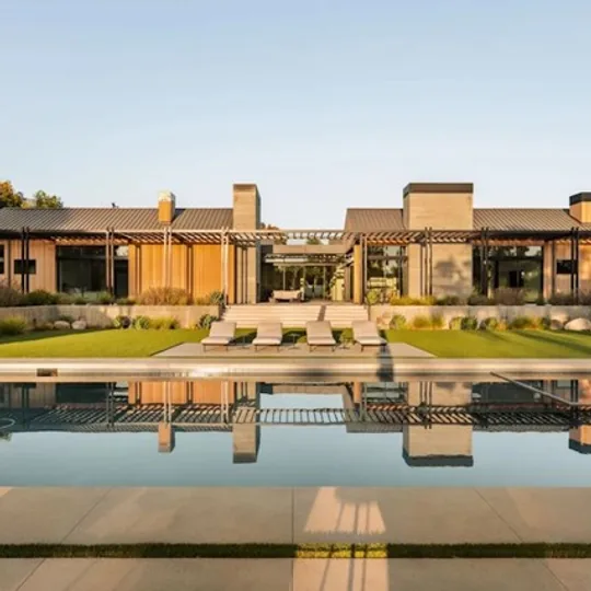 Sotheby's International Realty short-form post: a low modern estate with a long reflecting pool and loungers at golden hour.