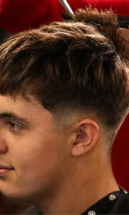 Sport Clips short-form post: a young man in profile showing a fresh tapered cut as a hand styles the top.