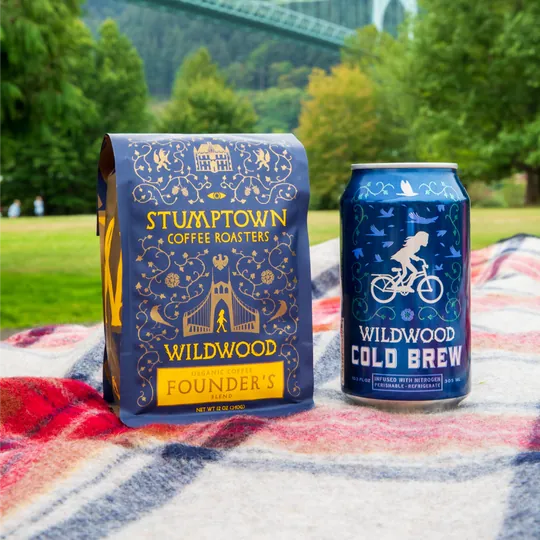 Stumptown Coffee Roasters short-form post: a coffee bag and a cold brew can on a picnic blanket in a park with a bridge behind.