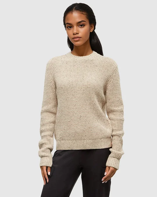 tentree short-form post: a woman in an oatmeal waffle-knit Morrell sweater and black trousers against a light grey studio background.