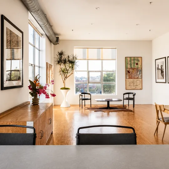 The Agency short-form post: a bright loft with a dining table, tall windows and framed art on brick walls.