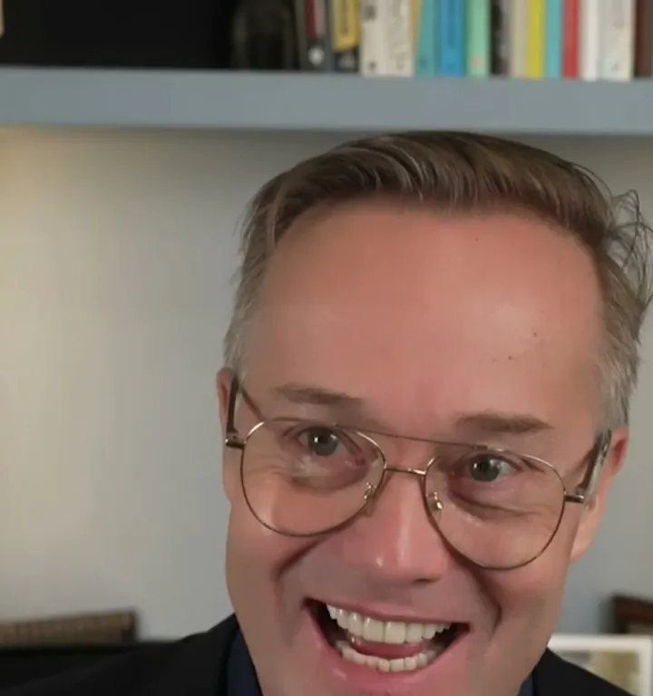 This Week in Startups short-form post: a man with glasses and a dark jacket laughing as he speaks, with bookshelves behind him.