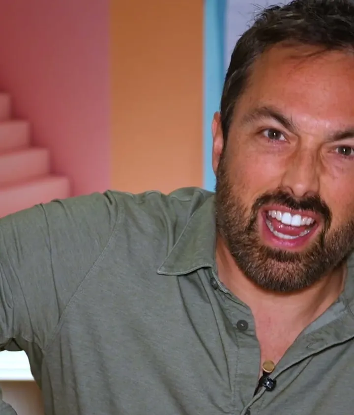 Veritasium short-form post: a bearded man in a grey shirt smiling and talking to camera against a pink and orange wall.