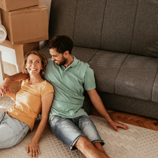 Windermere Real Estate short-form post: a couple sitting on the floor of a living room surrounded by moving boxes.